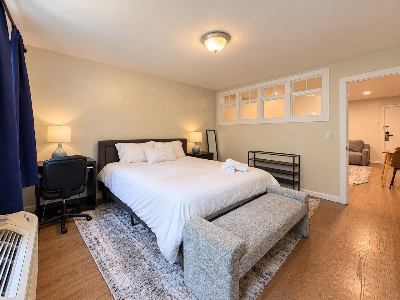 A bedroom with a bed, bedside tables, a desk, and a chair.