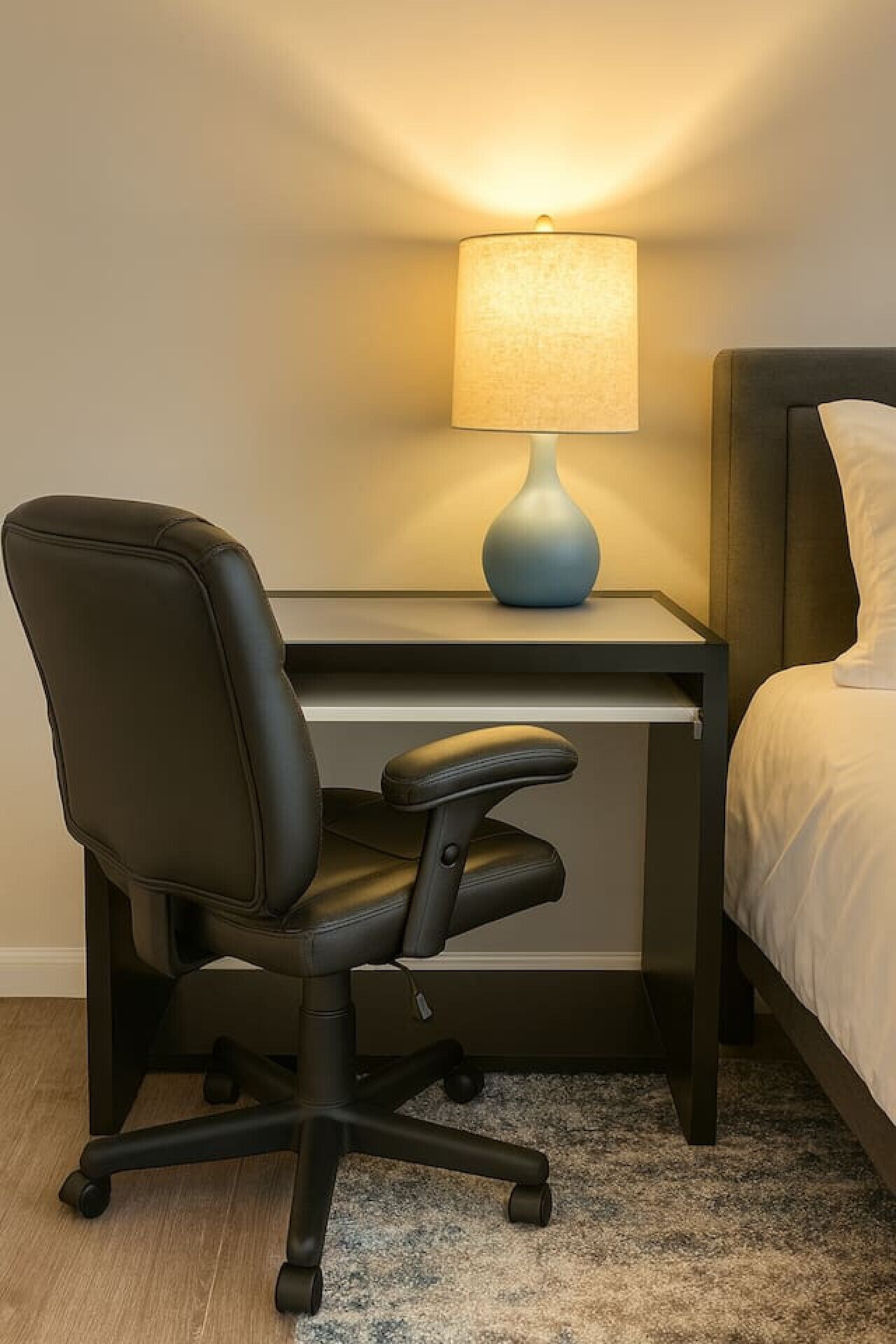 Une chambre d’hôtel équipée d’un bureau, d’un fauteuil de bureau noir, d’une lampe et d’un lit.