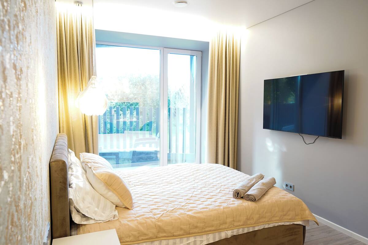 A bedroom with a bed, curtains, a TV, and a window.
