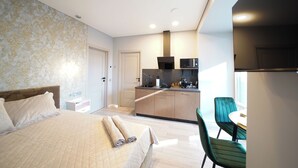 A modern hotel room with a bed, a small kitchenette, and a dining area. - Svaja ApartHotel & Spa (Šiauliai)