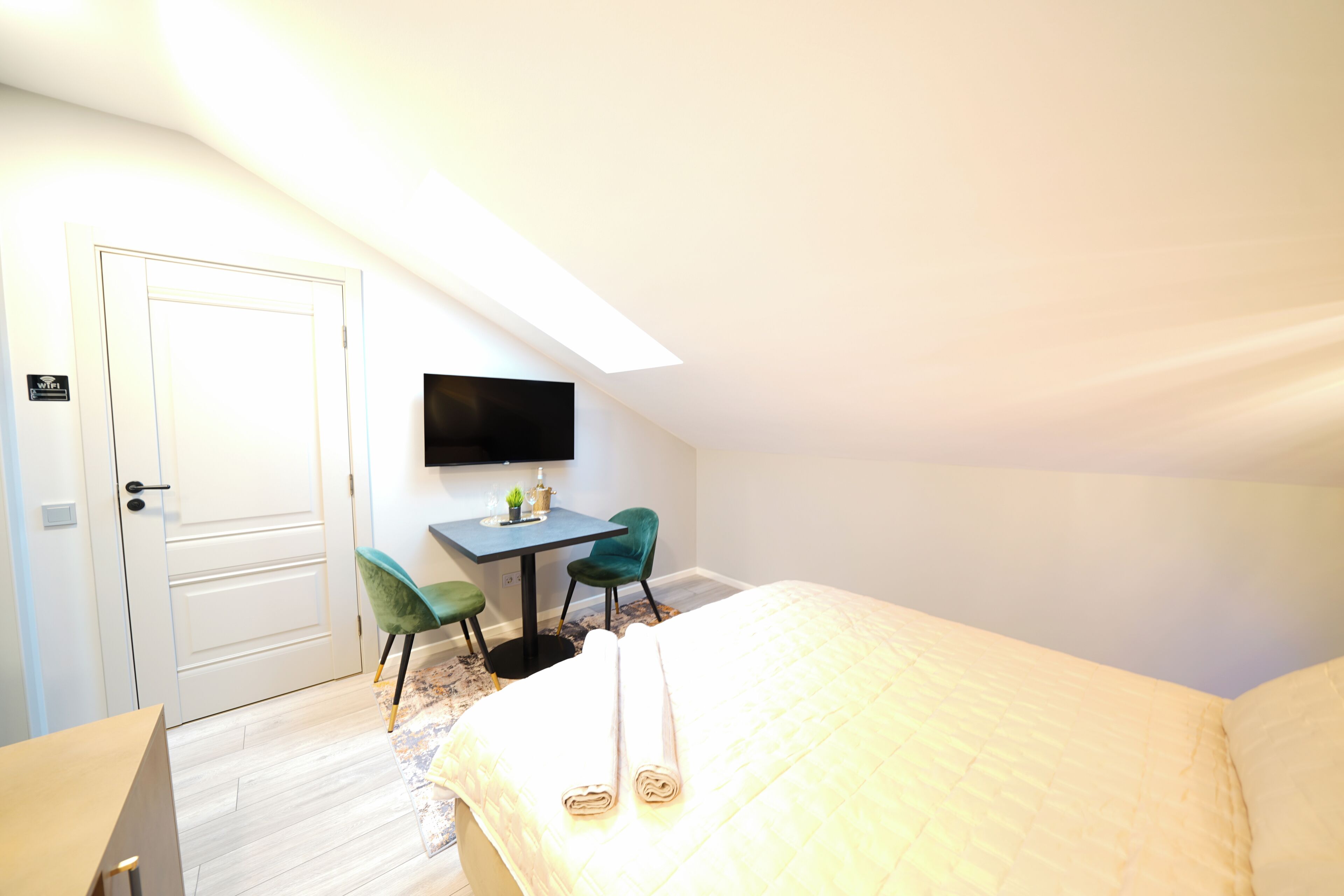 Un dormitorio con una cama, un escritorio, dos sillas, un televisor y una puerta.
