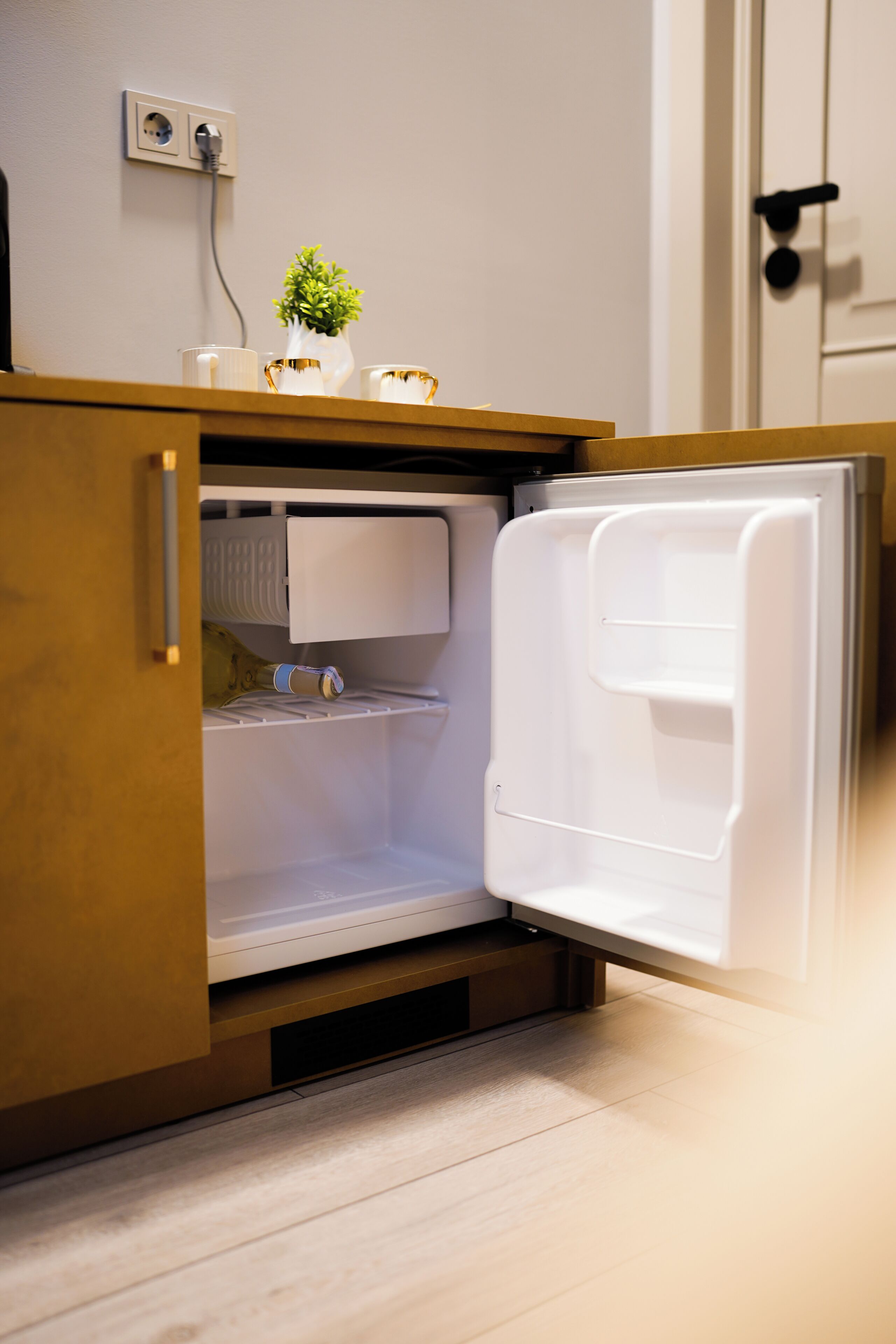A kitchen with a built-in refrigerator, a small potted plant, and a microwave.