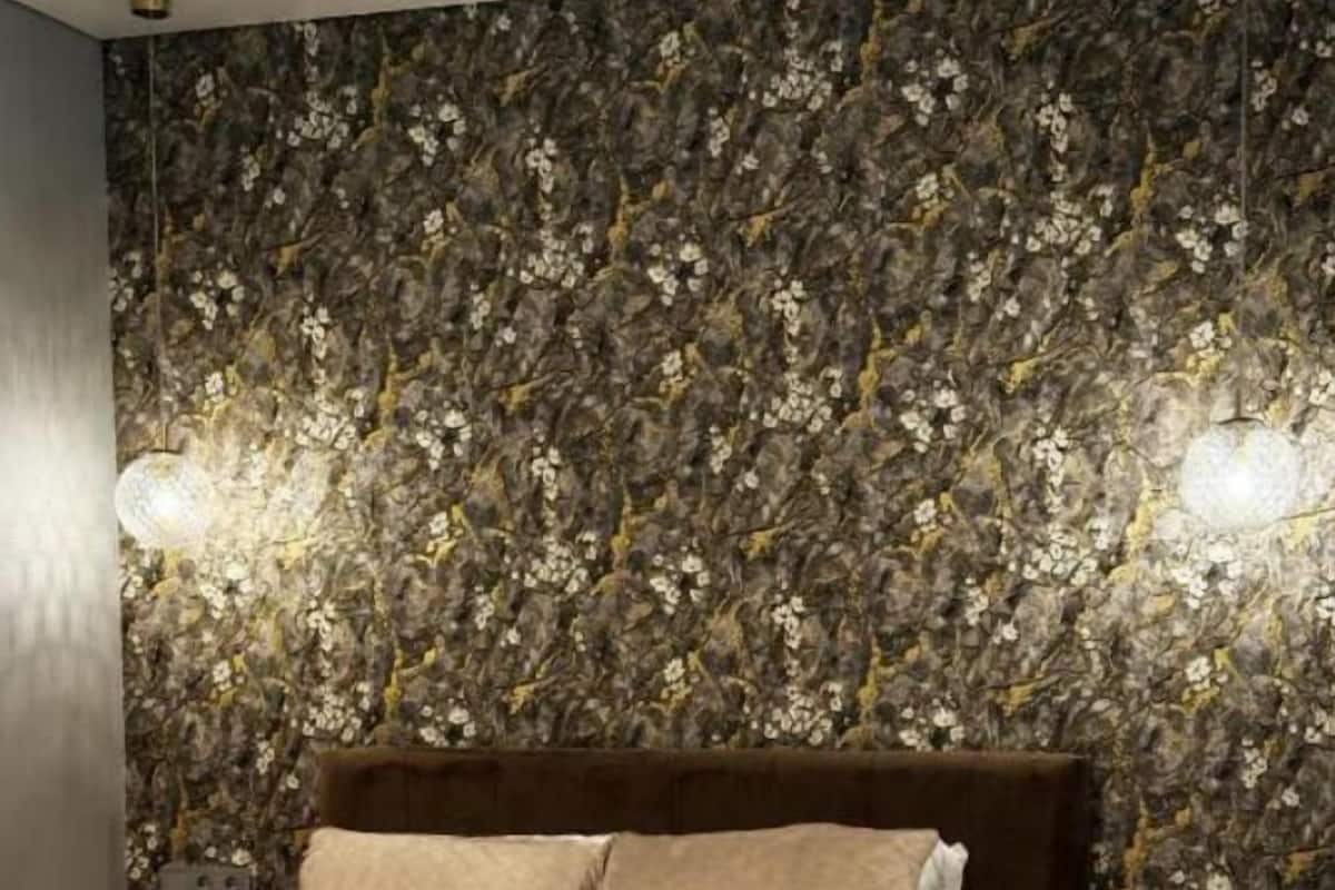 A bedroom with a floral wallpaper, a brown headboard, and two bedside lamps.