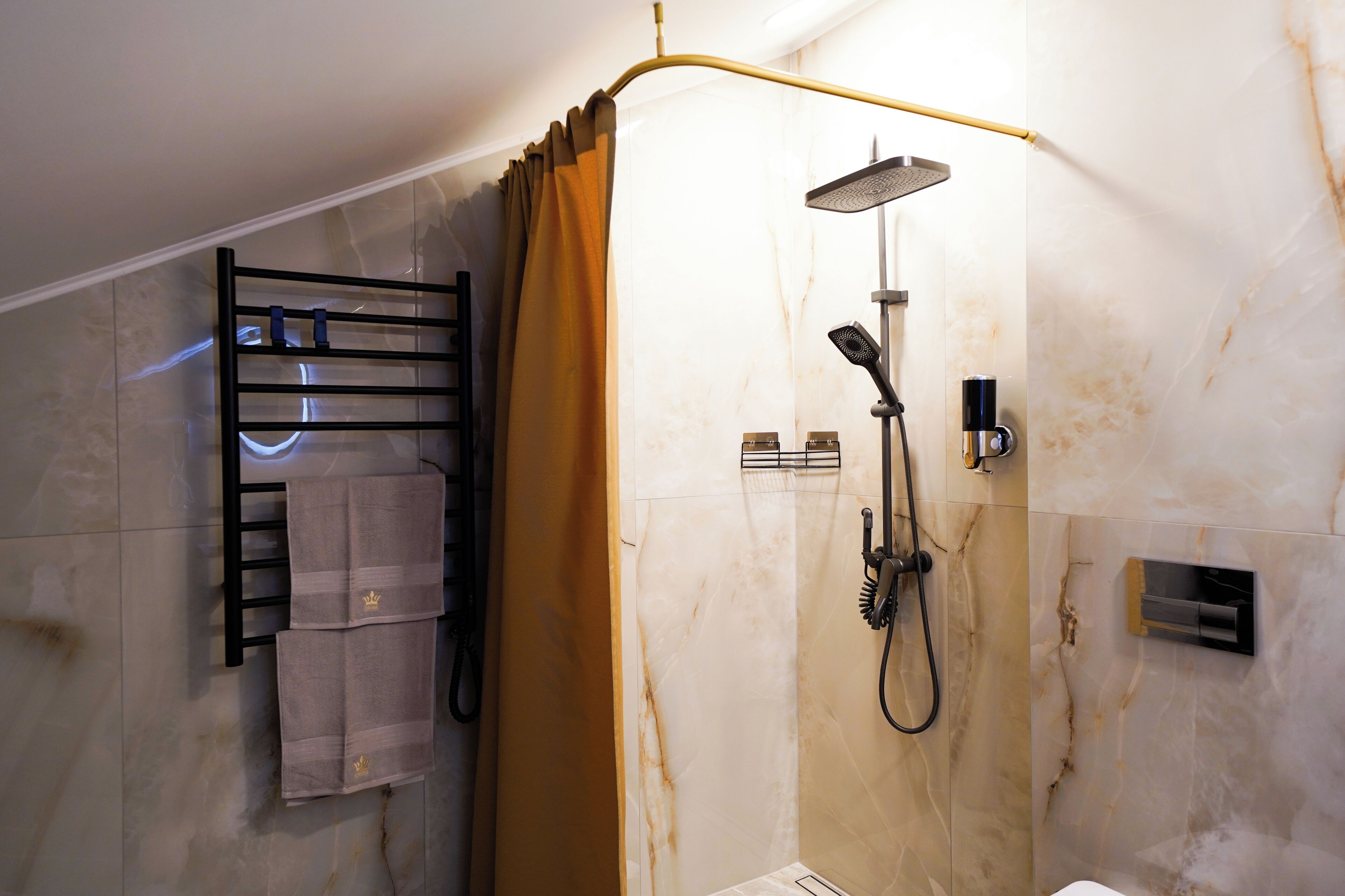 A modern bathroom with a glass shower enclosure, a towel rack with towels, and a marble wall.