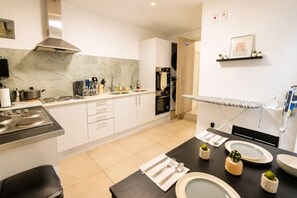 A modern kitchen with a stove, sink, and ironing board. - Cardiff Studio on Claude Road | Fast WiFi & Double Bed (Cardiff)