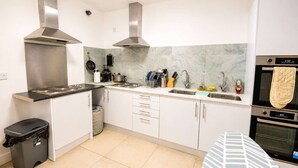 Una cucina moderna con elettrodomestici in acciaio inossidabile, una parete di fondo in marmo e un cestino nero.