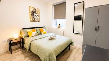 A bedroom with a bed, bedside tables, a window with a view, a wardrobe, and a painting on the wall.