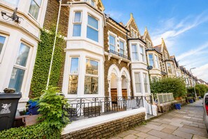 A row of Victorian-style terraced houses with bay windows, a stone facade, and a brick pathway. - Snug Studio with Fast WiFi (Cardiff)