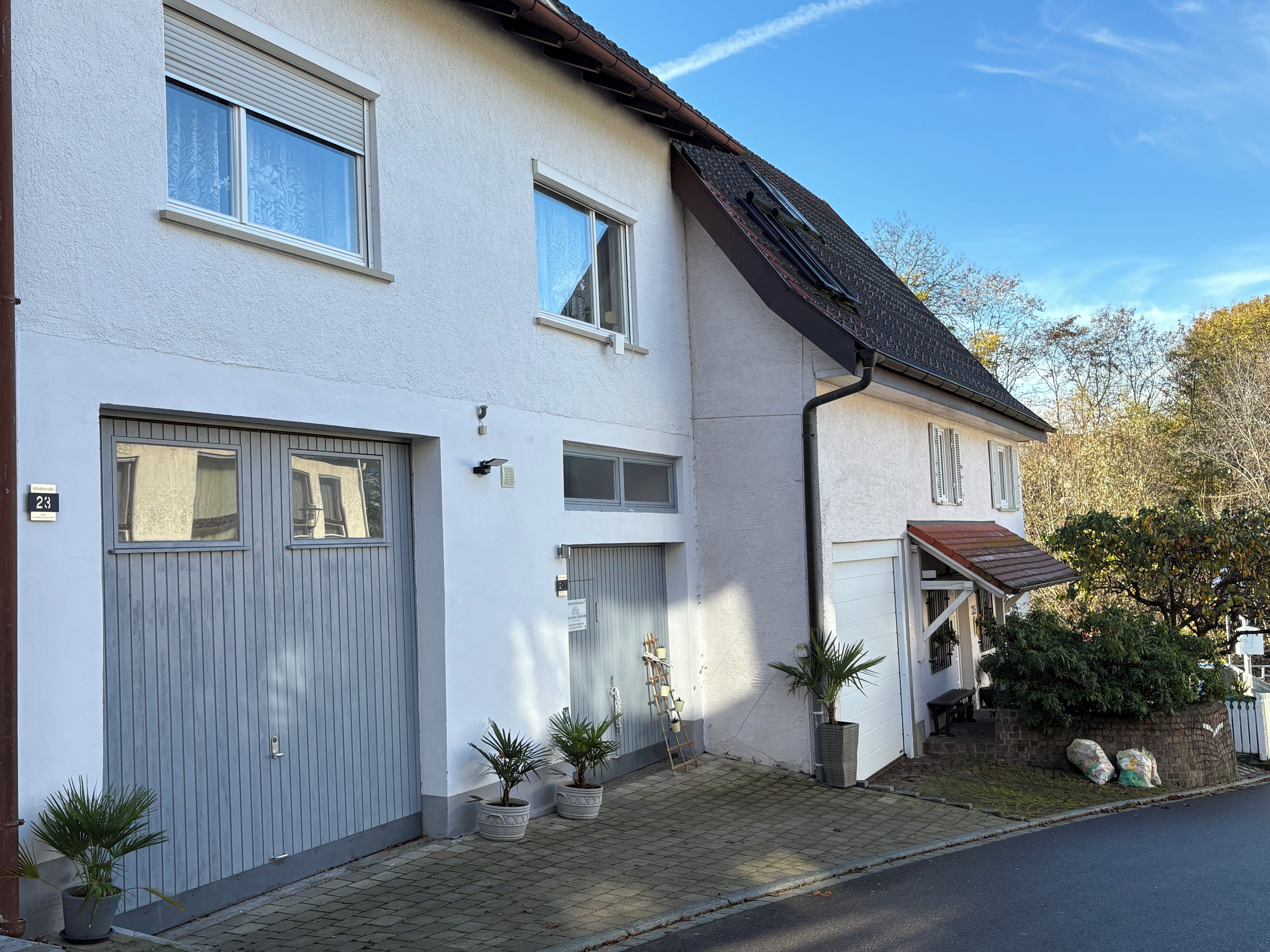 Ein zweistöckiges Wohnhaus mit Garage, Blumentöpfen und einem sichtbaren Hausnummernschild.