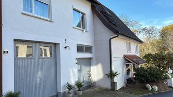 Ein zweistöckiges Wohnhaus mit Garage, Blumentöpfen und einem sichtbaren Hausnummernschild.