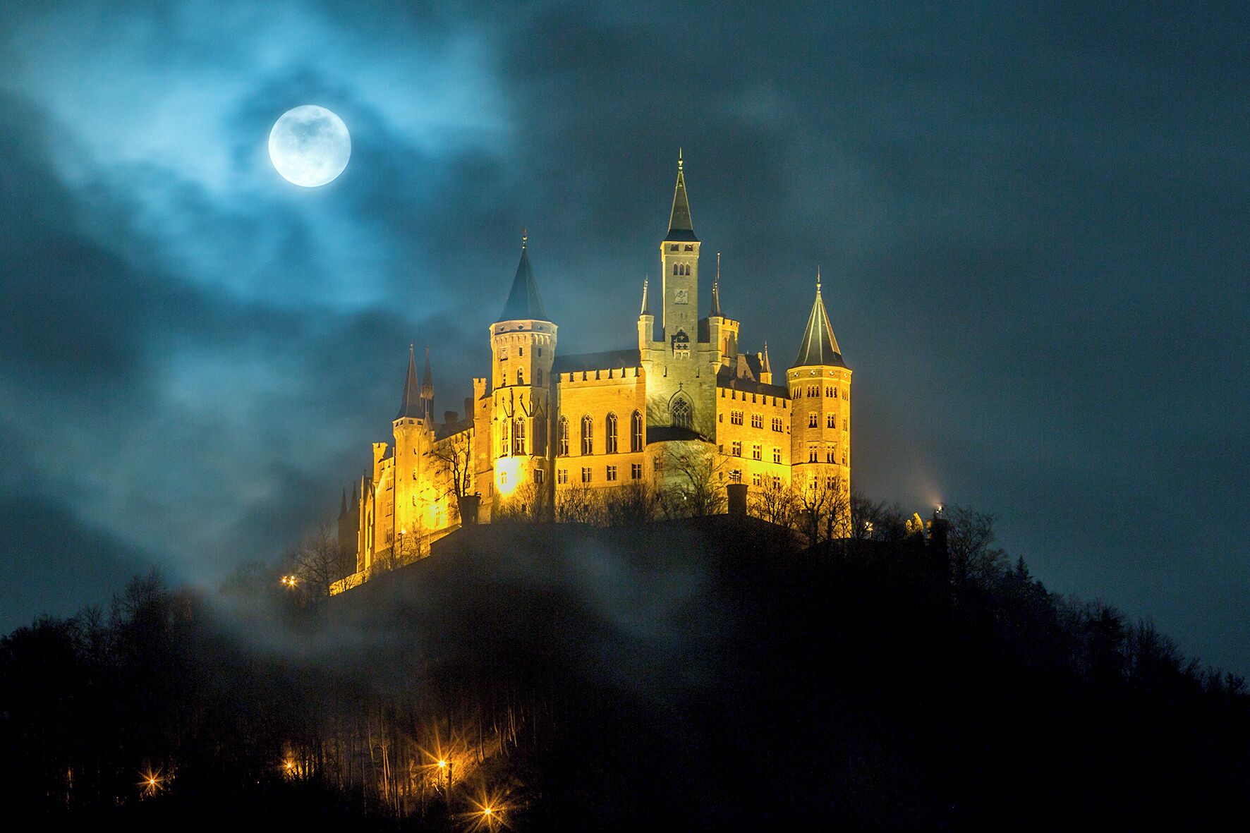 Un castillo con múltiples torres y la luna en el cielo.