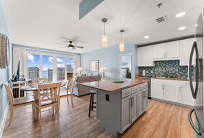 A modern kitchen with a central island, white cabinetry, and a large refrigerator. - Gulf View 3BR Resort Condo with 5 Pools (Panama City Beach)