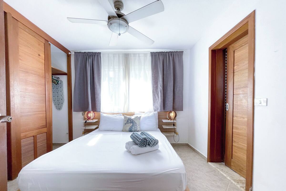 A bedroom with a single bed, a ceiling fan, and two bedside lamps.