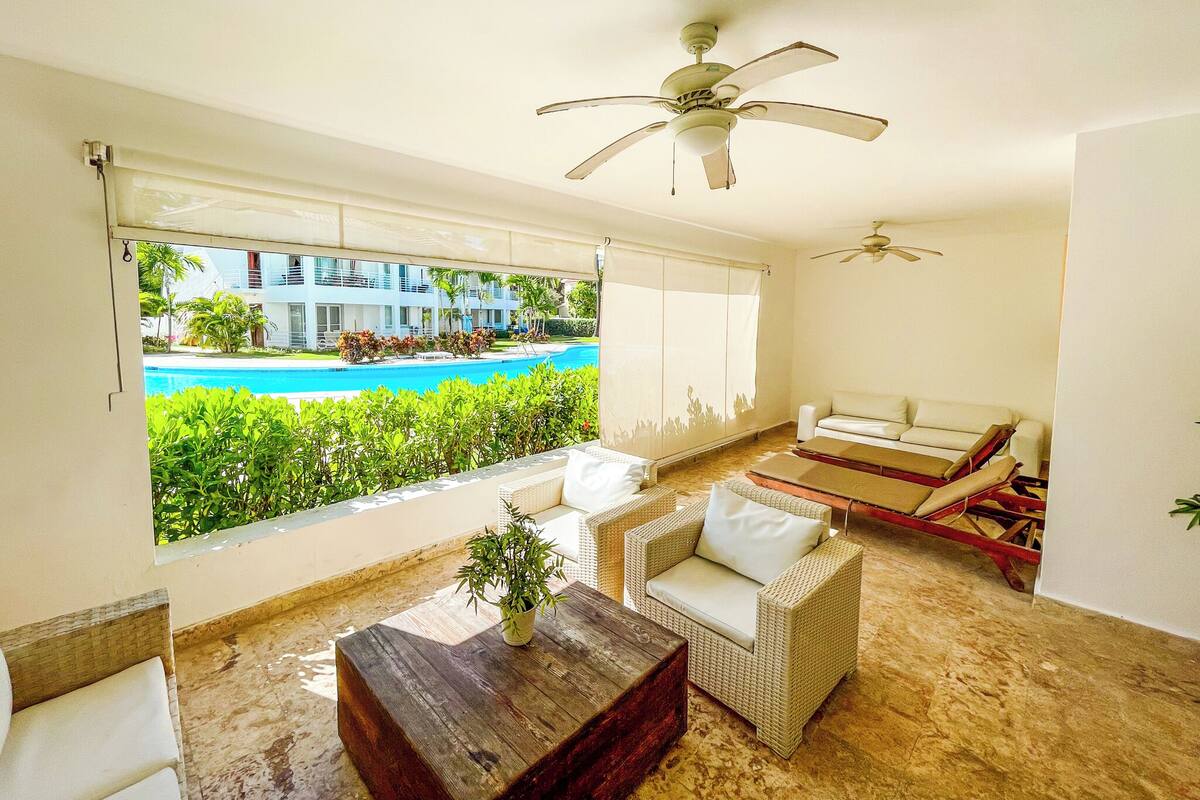 A spacious living area with a view of a swimming pool and a building in the background.