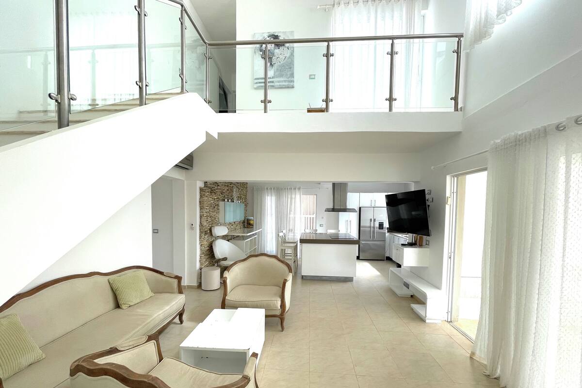 A spacious living area with a high ceiling, a dining area, and a kitchen.