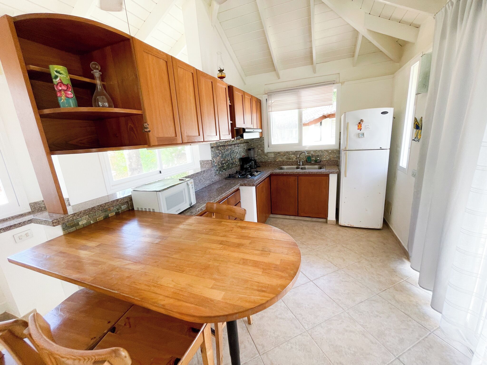 A kitchen with wooden cabinets, a white refrigerator, a microwave, and a sink.