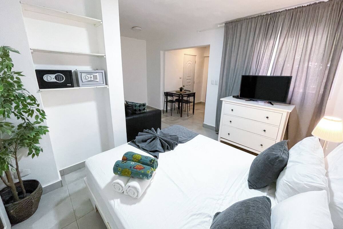 A hotel room with a bed, a TV, a desk, and a chair.