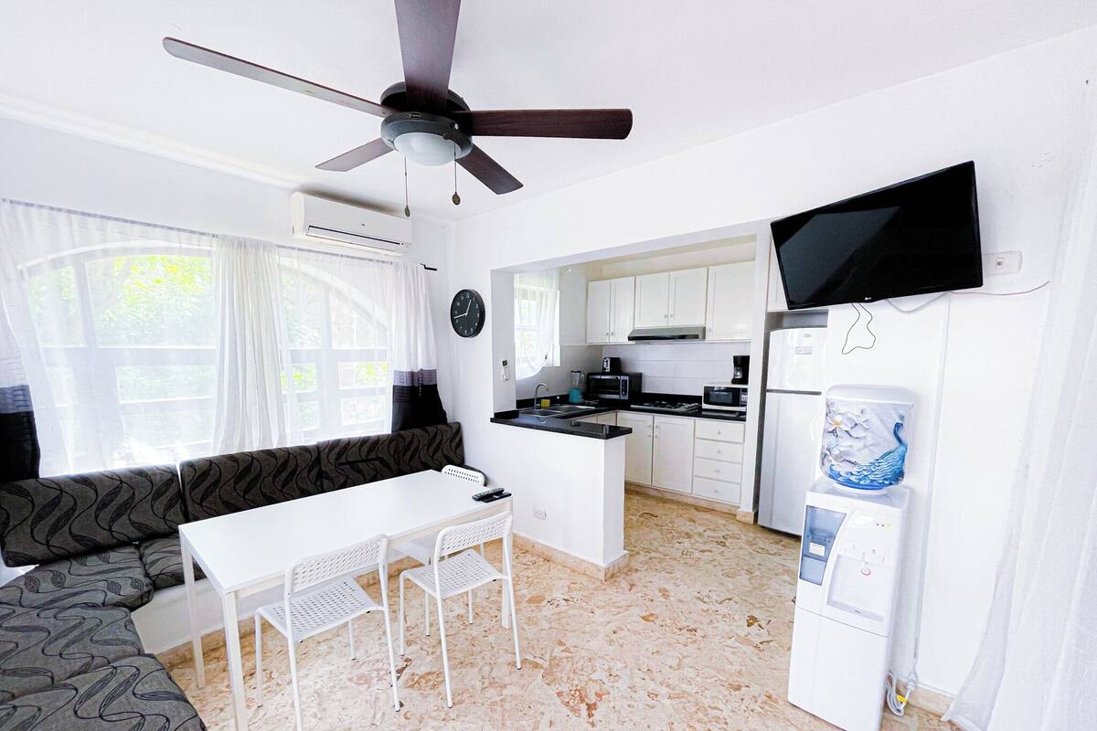 A compact kitchen with white cabinets, a black TV, and a water dispenser.