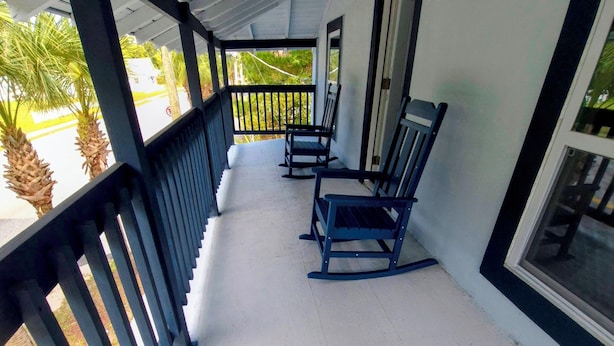 An upper front porch with a white floor, black railings, and two rocking chairs. - Zora's Sojourn (St. Augustine)