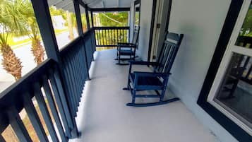 An upper front porch with a white floor, black railings, and two rocking chairs.