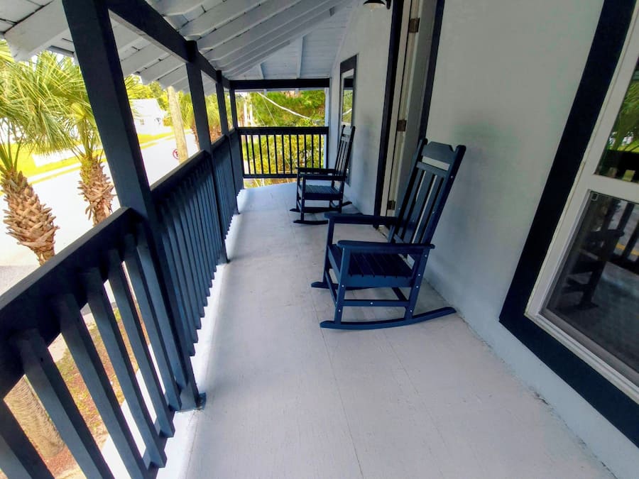 An upper front porch with a white floor, black railings, and two rocking chairs.