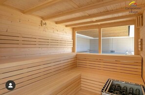 A wooden sauna with a bench, a window, and a view of an outdoor area. - La Petite For t Seaview Flat in Marbella (Finestrat)