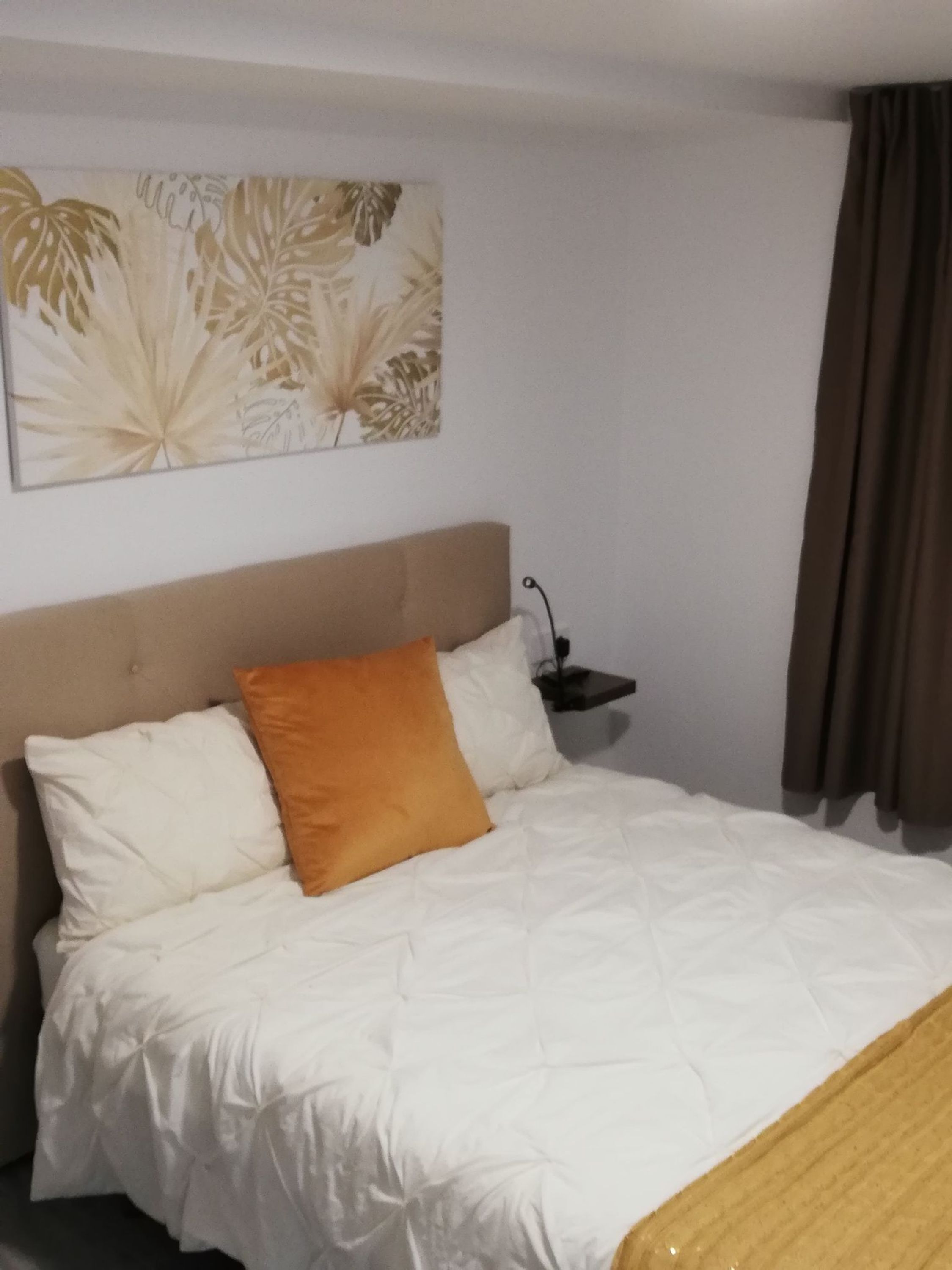 Quarto de hotel com cama, mesa de cabeceira e uma obra de arte pendurada na parede.
