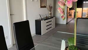 Ett modernt matområde med ett glasbord, svarta stolar och en orkidé i en kruka.