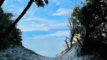 Une plage offrant une vue dégagée sur la mer, bordée d’arbres et d’un sentier rocheux.