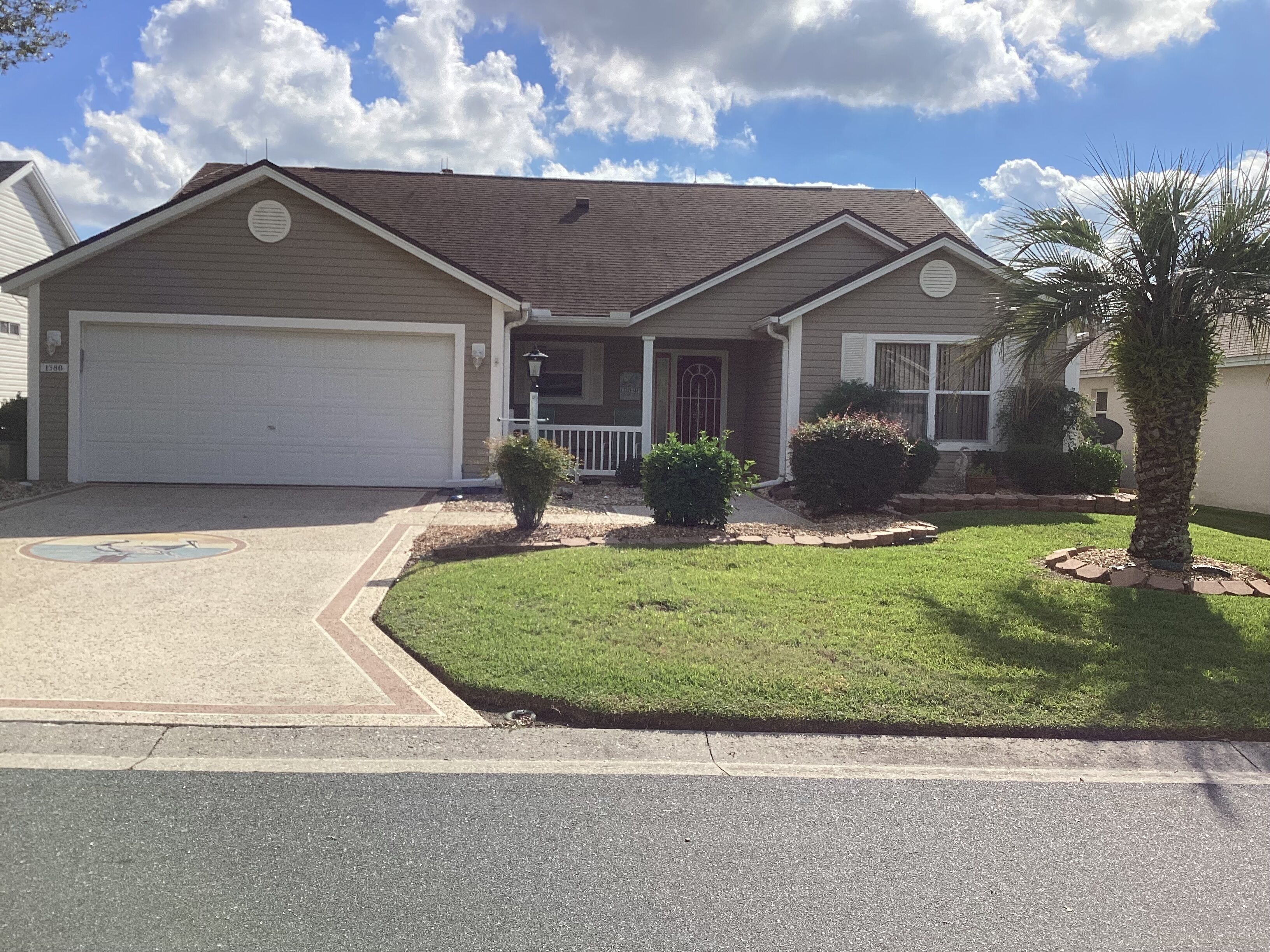 A two-story house with a garage, a front porch, and a well-maintained lawn.