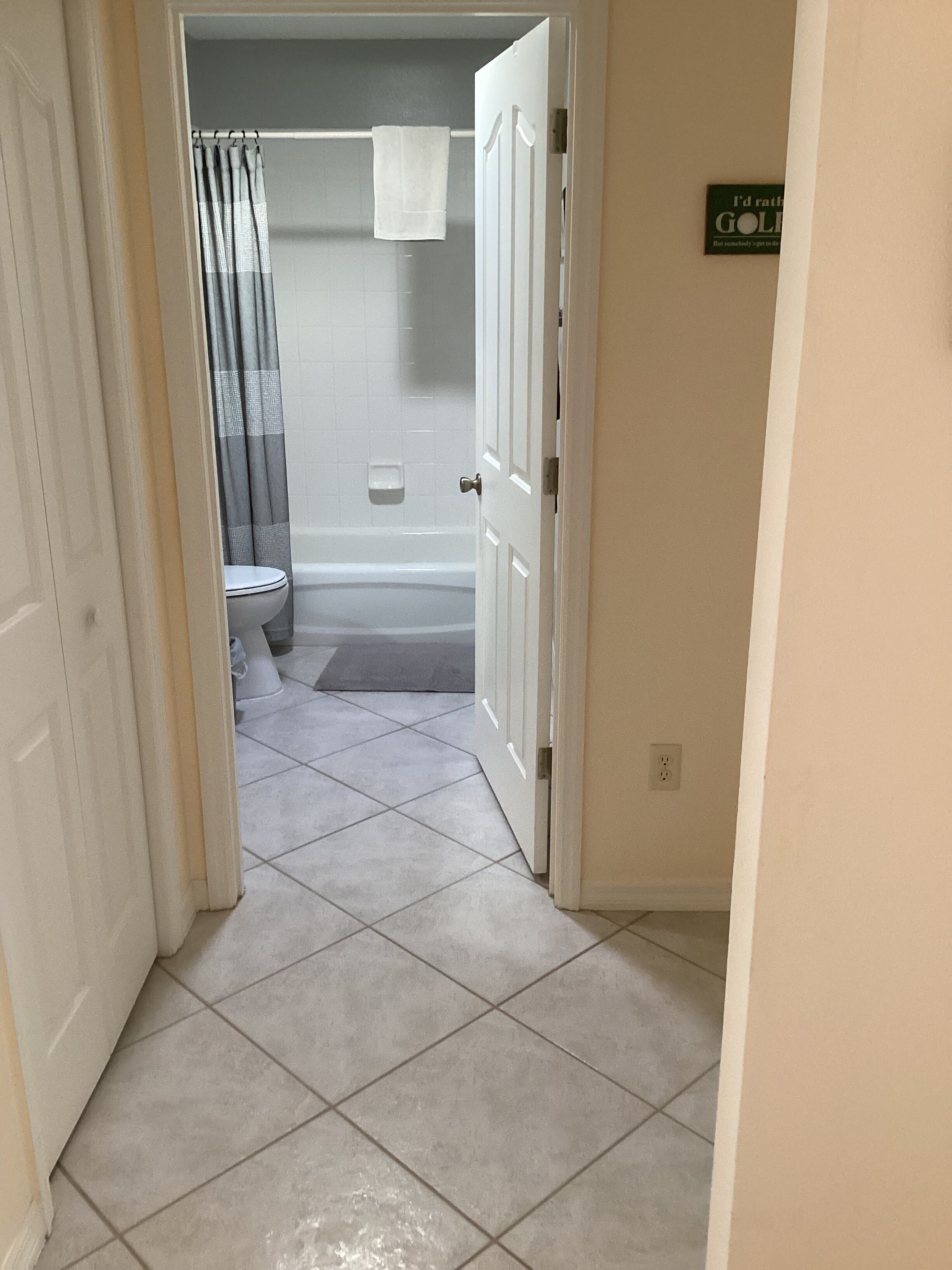 A bathroom with a shower, toilet, and a towel hanging on the wall.