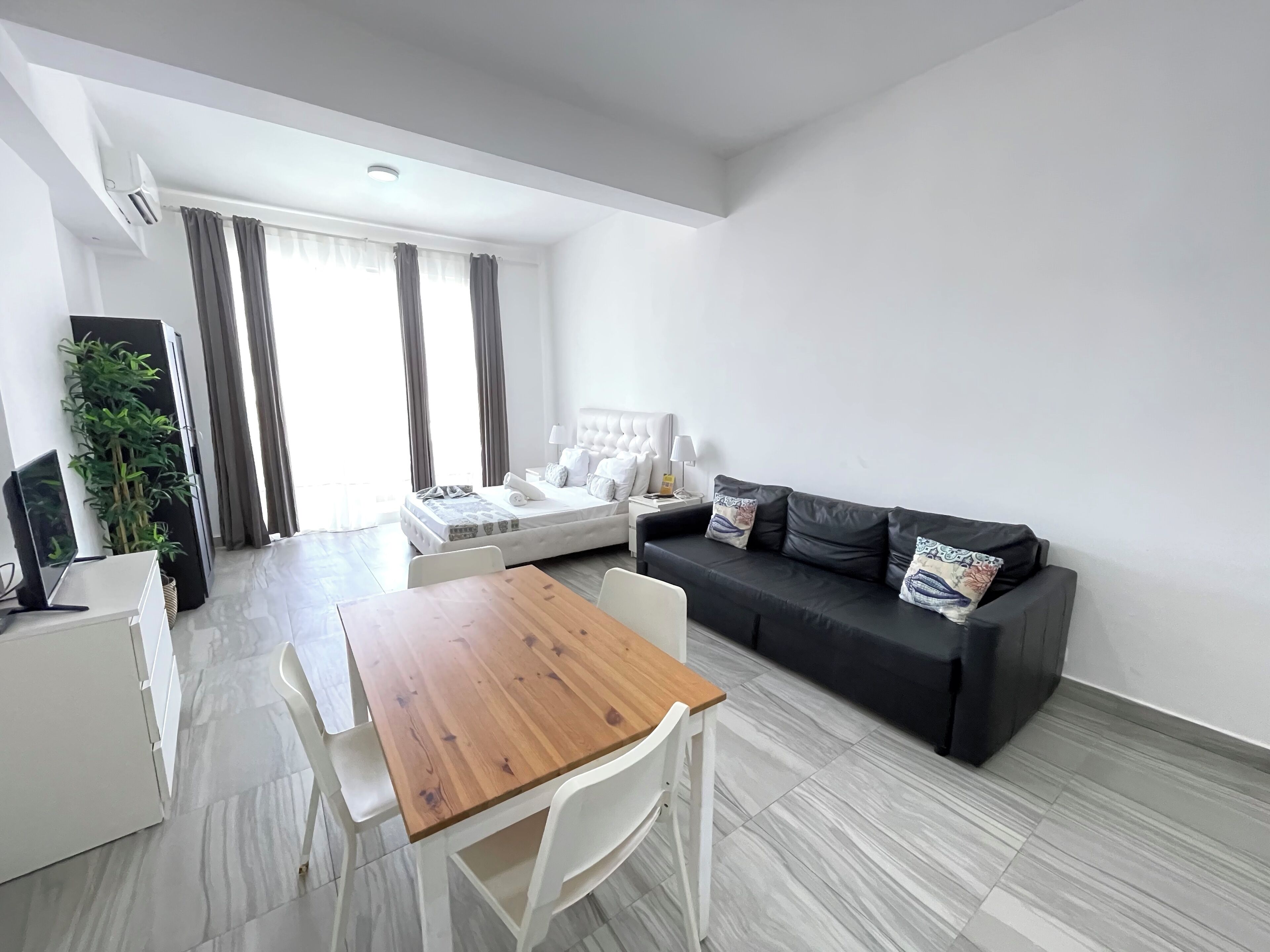 A modern living room with a sofa, a dining table, and a TV.