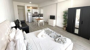 A modern hotel room with a bed, a small dining area, a kitchenette, and a wardrobe. - MINI STUDIOS BEACH (Punta Cana)