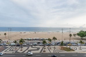 Ein Parkplatz am Strand mit Autos, Palmen und Blick auf den Strand und den Ozean.