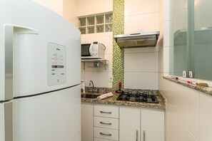 A compact kitchen with a built-in microwave, a gas stove, and a sink. - Plaza Copacabana - Conforto e Praia. (Rio de Janeiro)