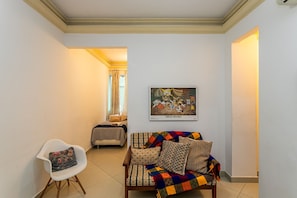 Una sala de estar con sofá, sillón, cama y un cuadro en la pared.
