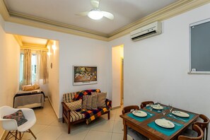 A cozy living room with a sofa, a dining table set for two, and a ceiling fan. - Plaza Copacabana - Conforto e Praia. (Rio de Janeiro)
