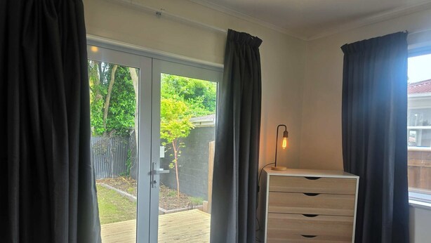 A bedroom with a bed, a dresser, and a window with curtains.