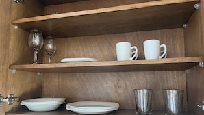 Ein Holzkabinent mit Regalen, auf denen Teller, Tassen und Gläser stehen.