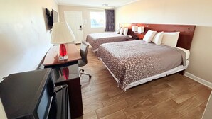 A hotel room with two beds, a desk with a lamp, a TV, and a wooden floor. - Western Motel (Dawson)