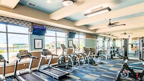Une salle de sport équipée de tapis de course, de vélos elliptiques et de matériel de musculation.