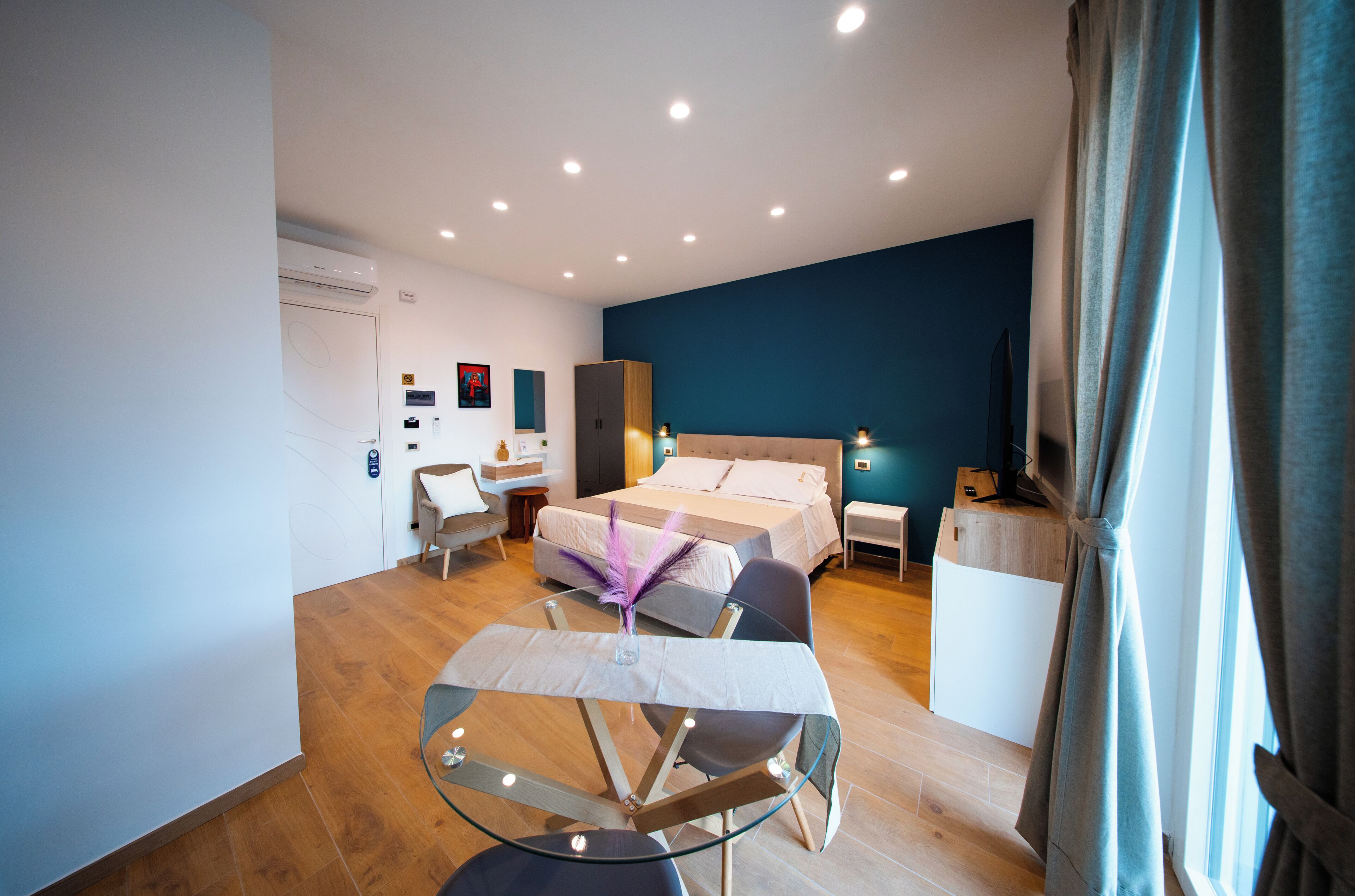 Une chambre d’hôtel moderne équipée d’un lit, d’un bureau, d’une chaise et d’une petite table sur laquelle se trouve un vase.