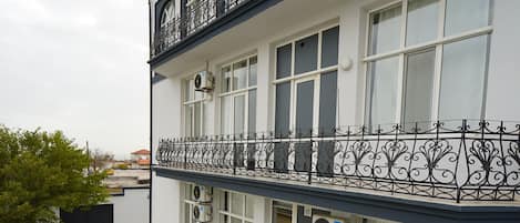 A multi-story building with balconies, air conditioning units, and a paved courtyard.
