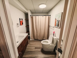 A compact bathroom with a toilet, a sink, and a shower curtain.