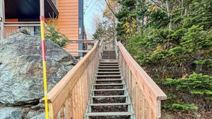 Un escalier en bois menant à un bâtiment doté d’un balcon.