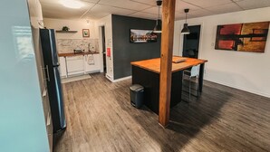 Une cuisine moderne avec un îlot central en bois, des meubles blancs et un plan de travail noir.