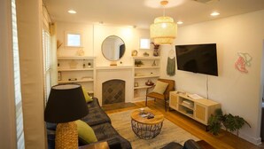 Ein Wohnzimmer mit Sofa, Couchtisch, Fernseher, Kamin, Regalen und einem Spiegel.