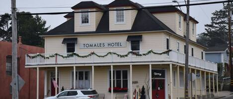 Un edificio di due piani con un cartello che riporta 'TOMALES HOTEL' e una porta rossa.