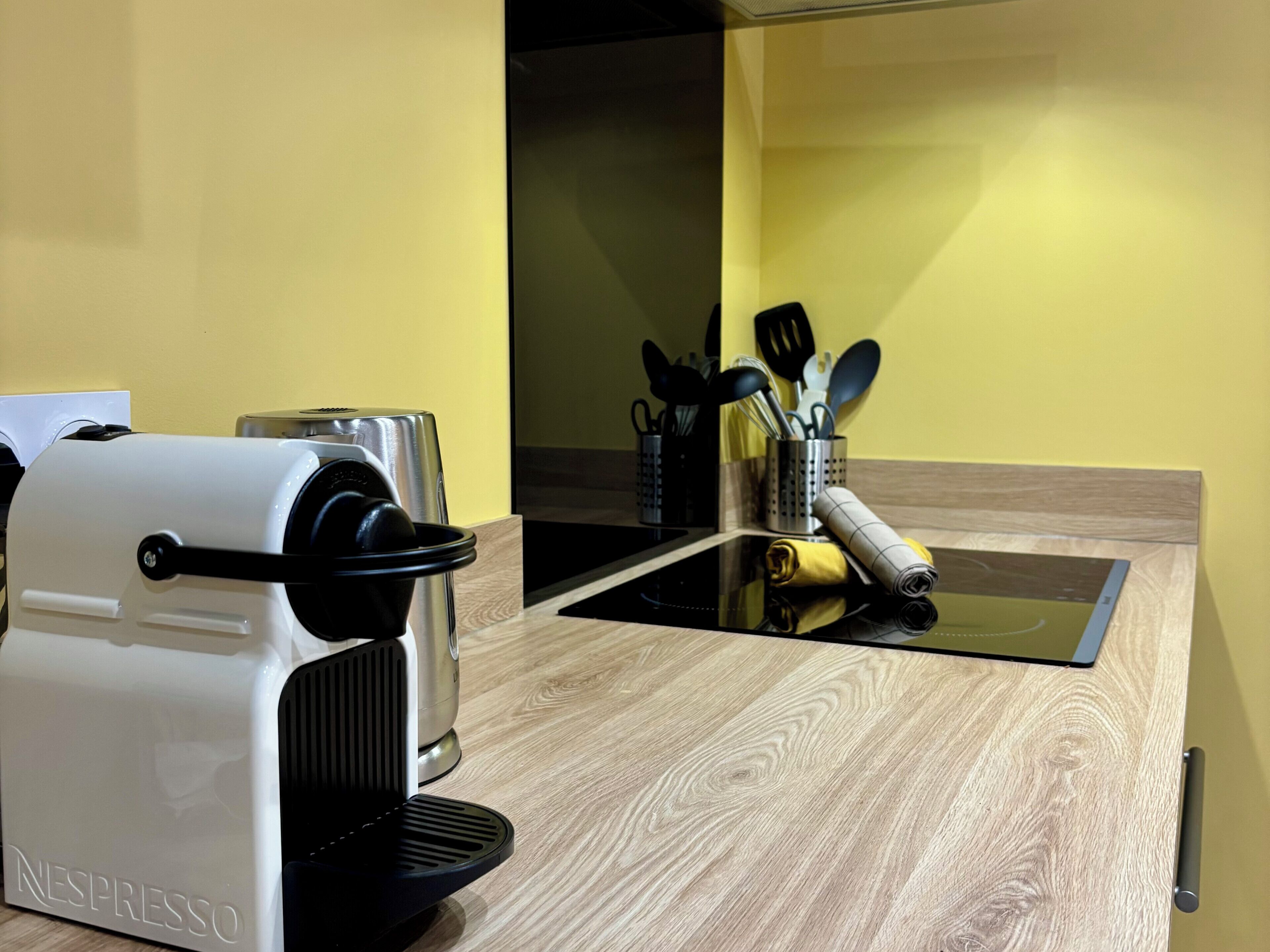 Une cuisine équipée d’une machine à café Nespresso, d’un grille-pain et d’un plan de travail en bois.