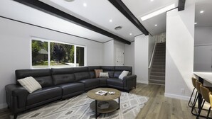 Ein modernes Wohnzimmer mit einem Ecksofa, einem Couchtisch und einer Treppe, die in eine obere Ebene führt.